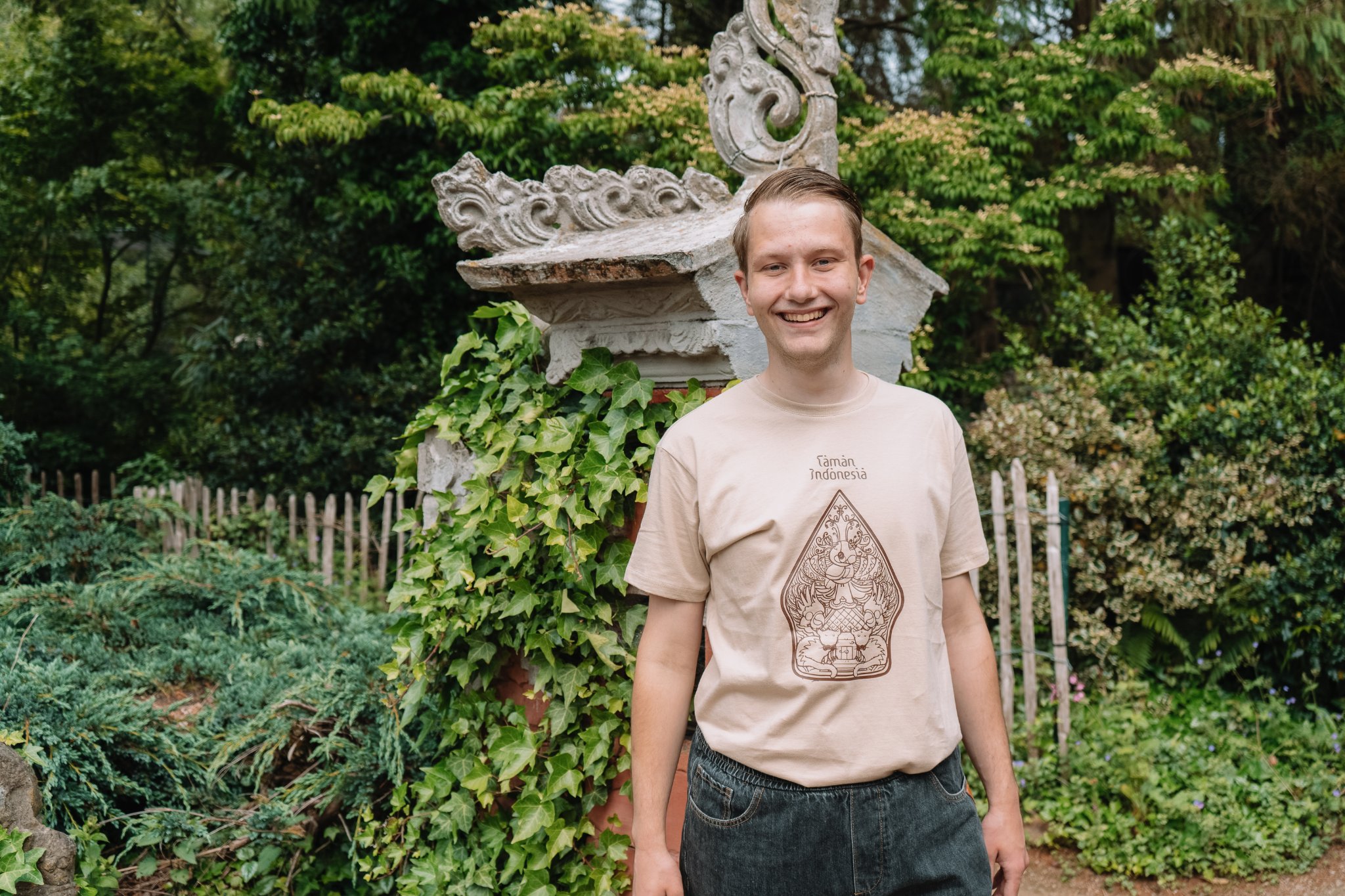 Een kaki T shirt met een wayang gunungan afbeelding speciaal ontworpen voor Taman Indonesia. Te verkrijgen in de maten XS, S, M, L.